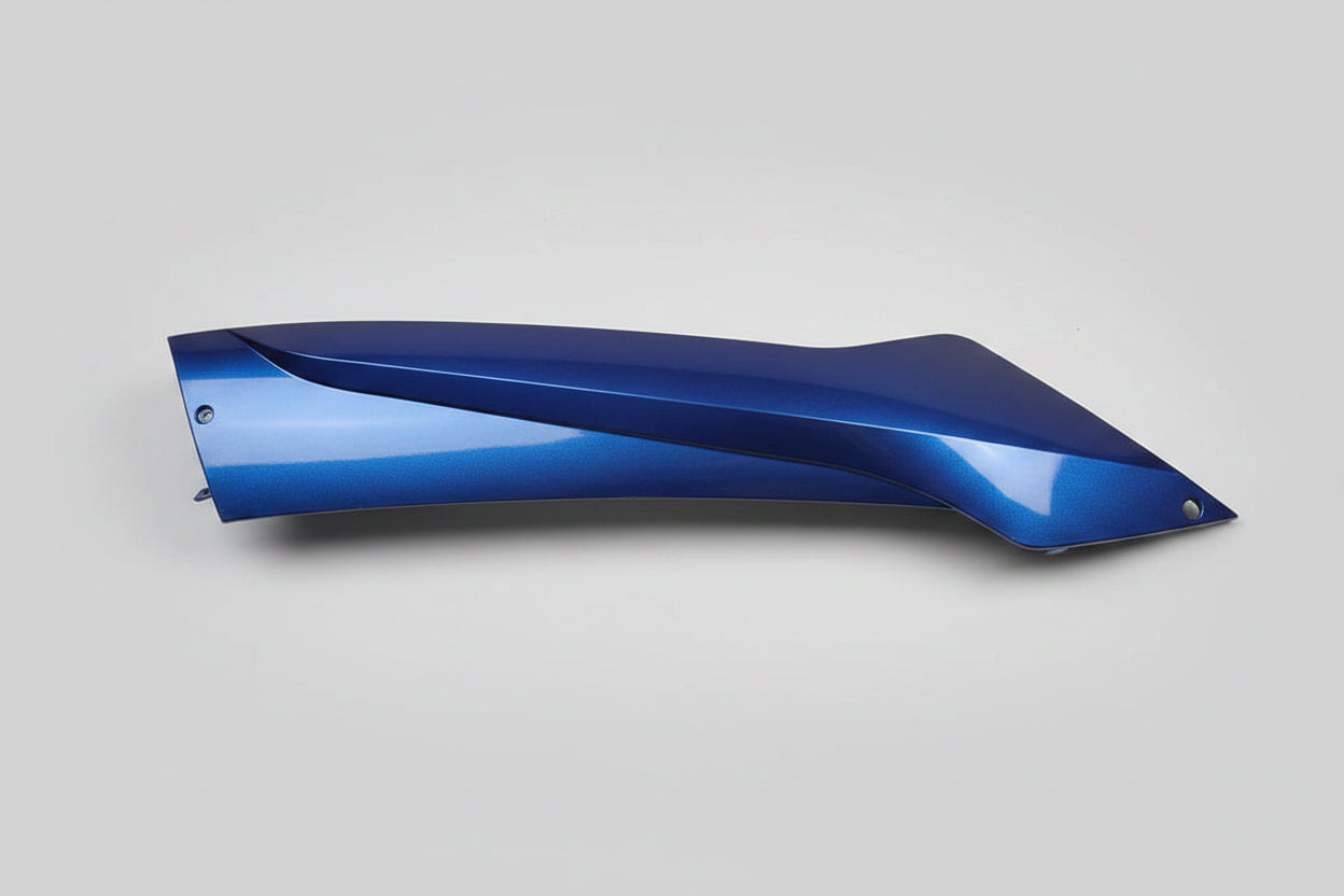 Blue plastic car part on a person's lap with a desk in the background