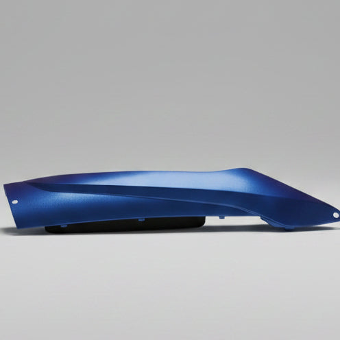 Blue motorcycle fender on a red surface with a person wearing jeans sitting nearby.