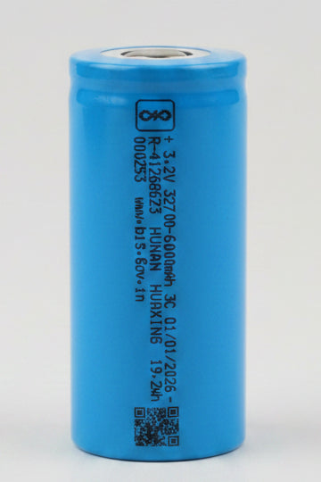 Blue cylindrical battery on a red surface with a blurred background