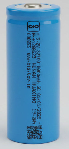 Blue cylindrical battery on a red surface with electronic devices in the background