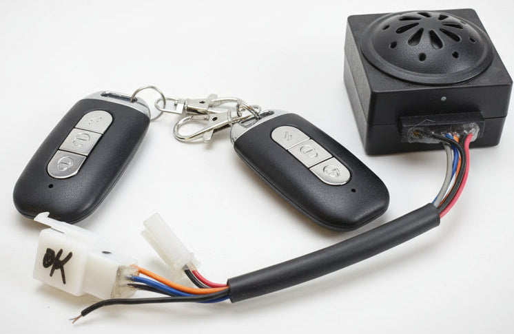 Car key fob, remote control, and electronic device on a red surface