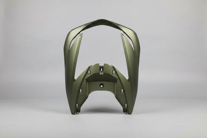 A motorcycle fairing or body panel with a dark olive green finish, photographed on a light-colored tiled floor with other parts and materials scattered around.