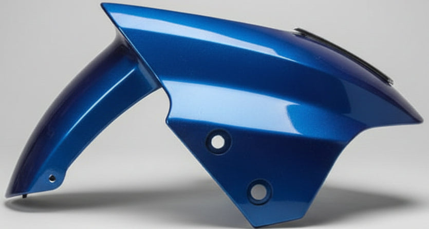 Blue motorcycle fender on a desk with a pen and paper in the foreground